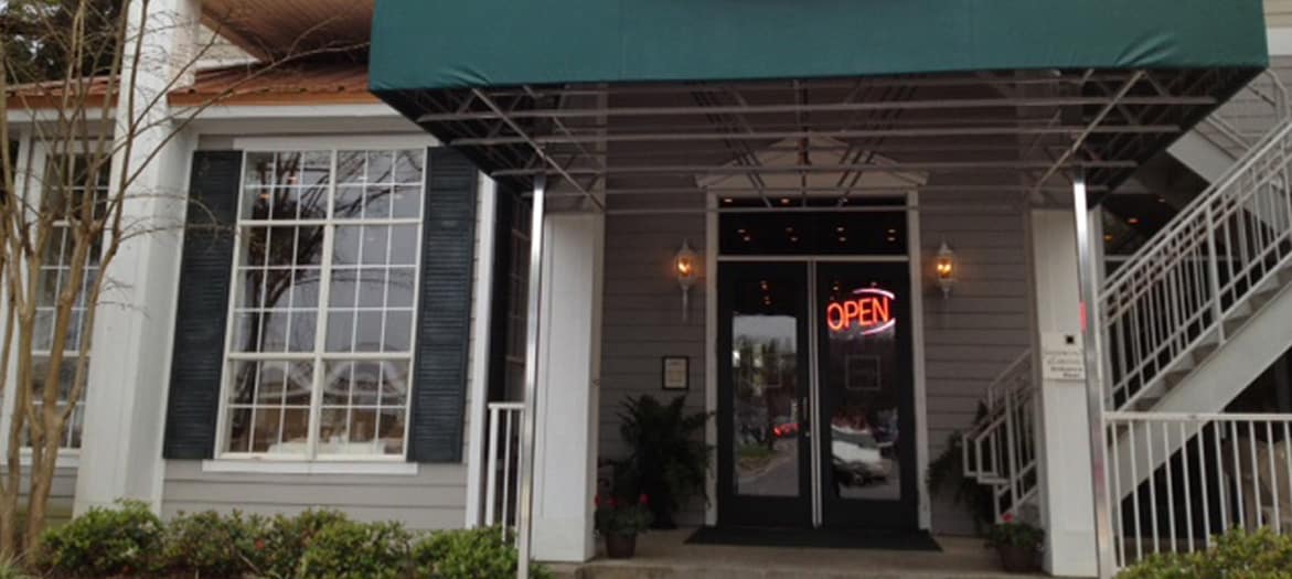 The image shows the entrance of a building with a green awning. A neon